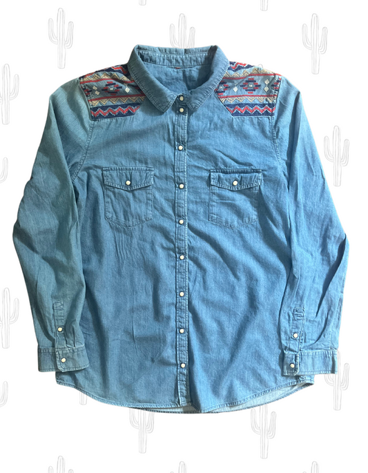 Front image of chambray pearl snap button up with red, white, yellow and blue embroidery on light background.