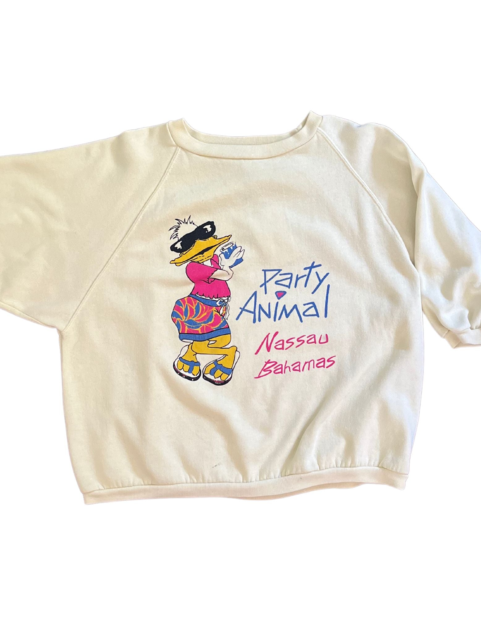 Front image of light yellow sweatshirt that reads party animal, nassau bahamas featuring a duck wearing sunglasses on a white background.