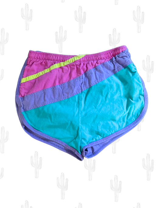 Front image of purple, pink, yellow and teal short gym shorts on light background.