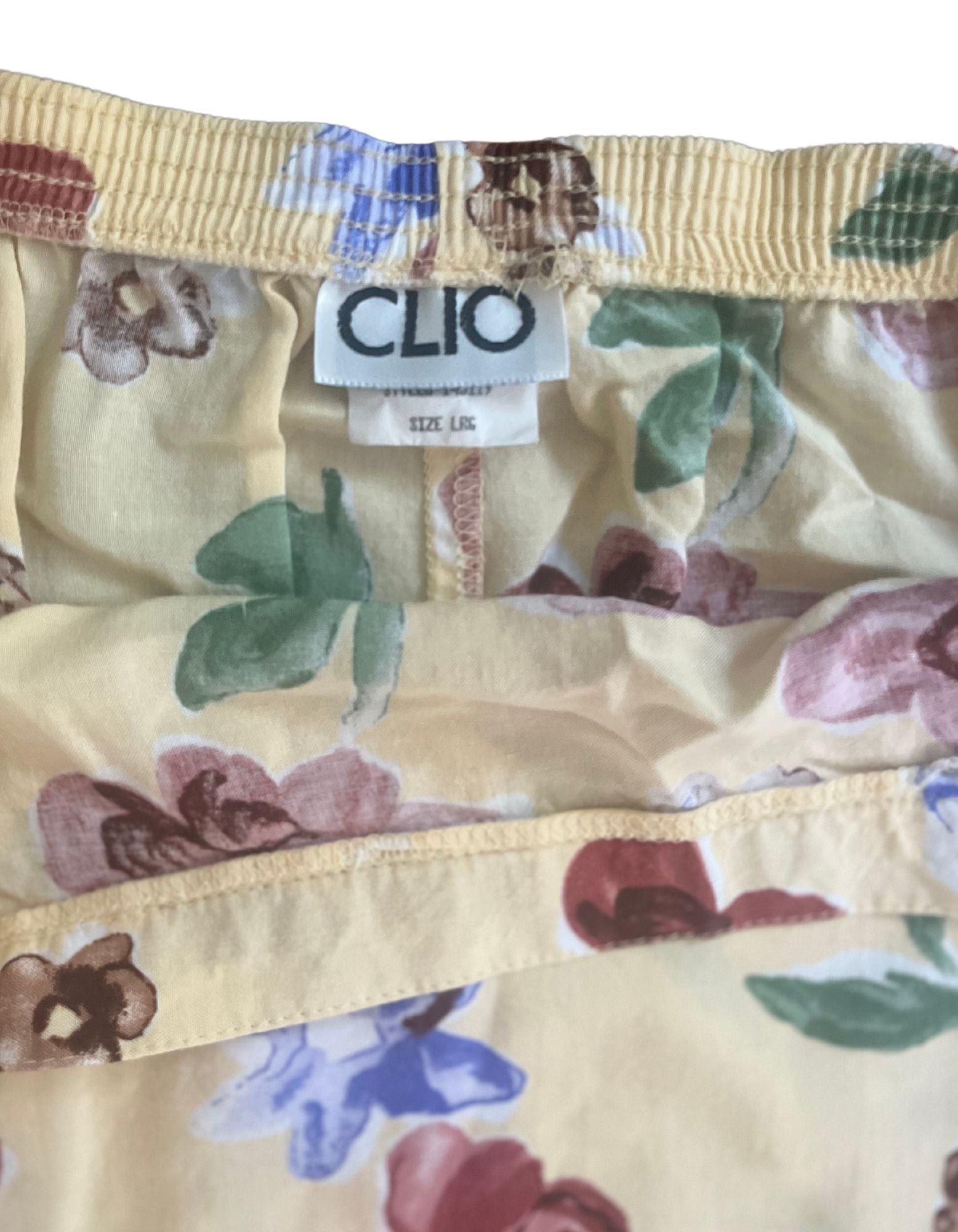 Close up image of tag of yellow floral pale yellow skirt with elastic waistband on white backgrouhd.