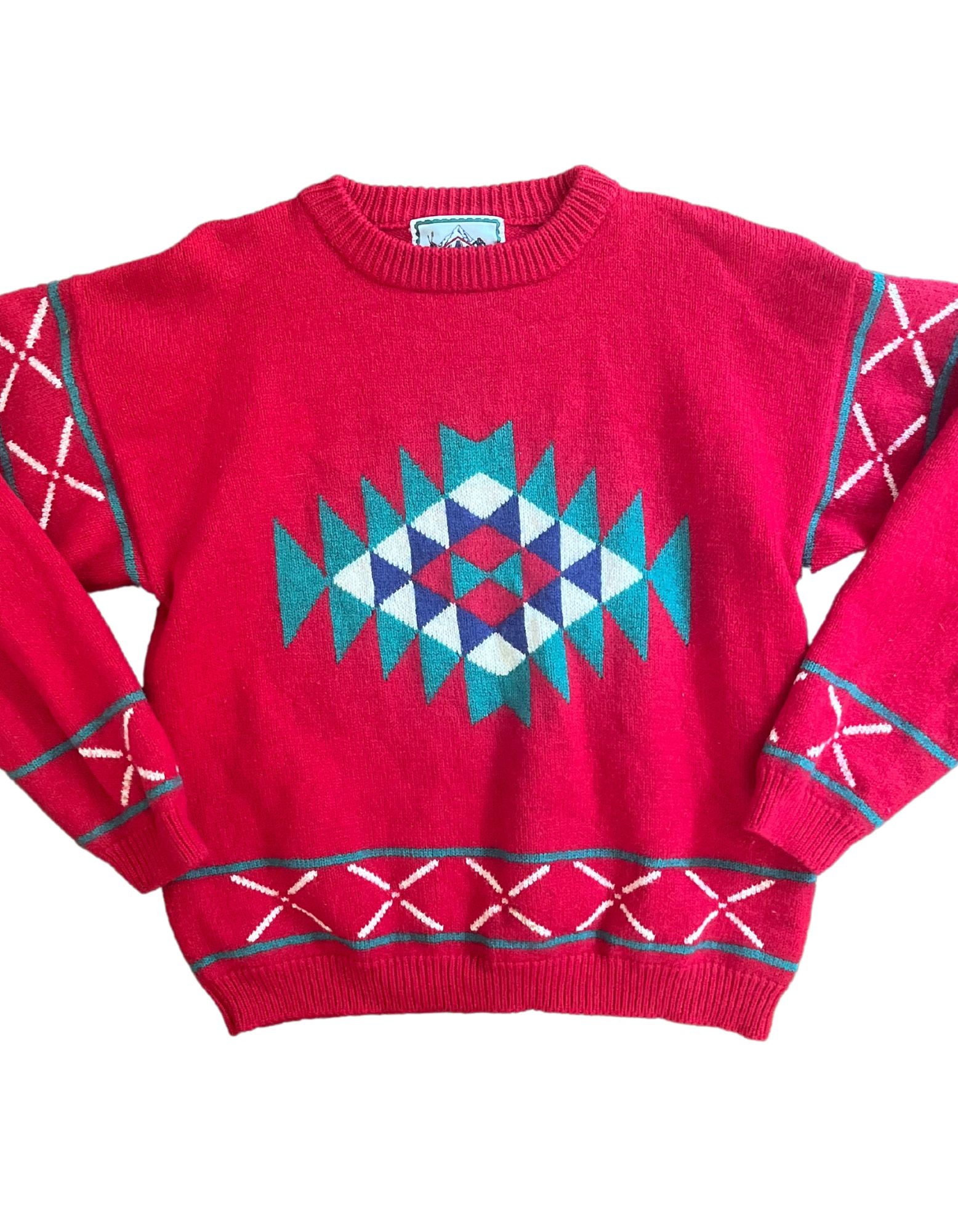 Front image of red sweater with teal, white and blue tribal print design on white background.