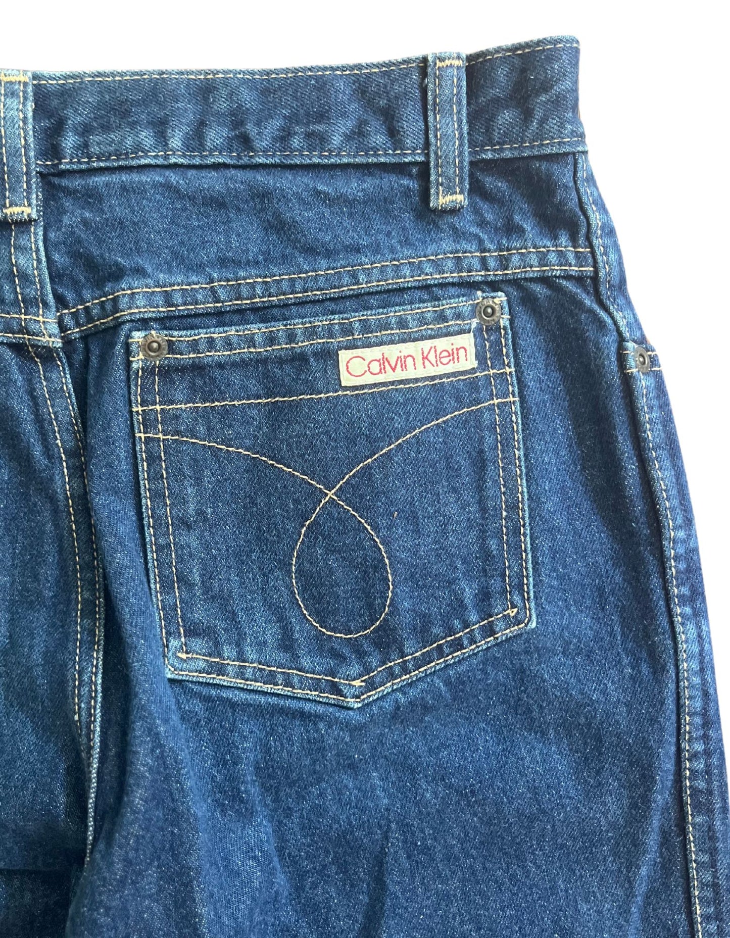 Back pocket image of dark vintage calvin klein jeans on white background.