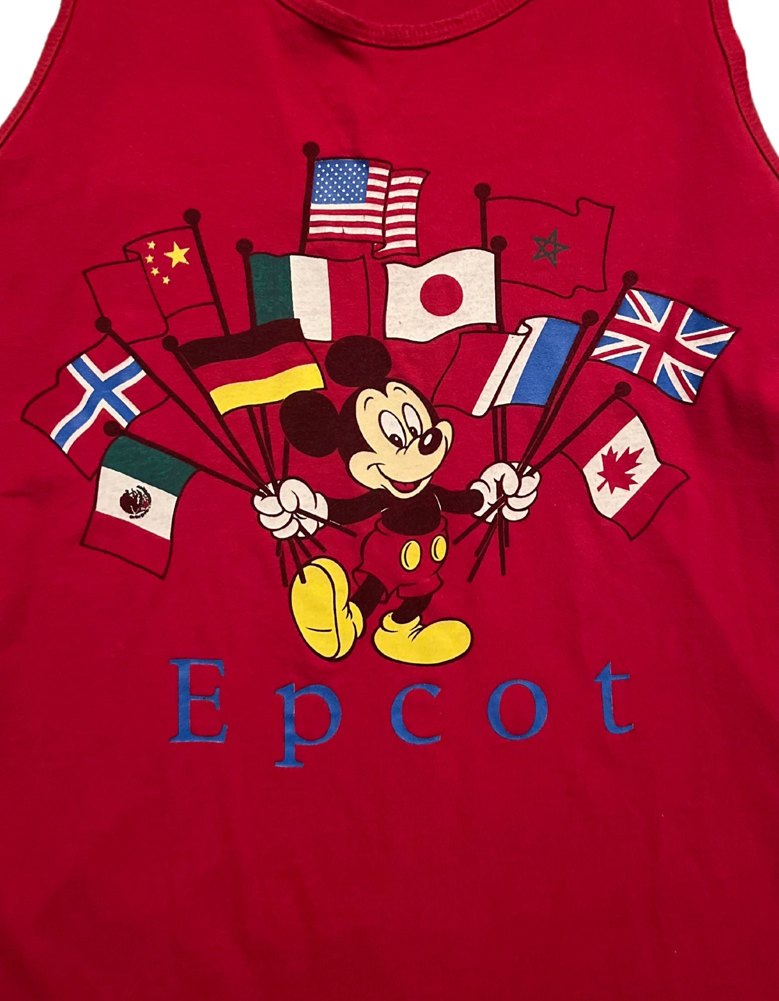 Close up image of red mickey mouse epcot tank top with multiple countries flags on white background.