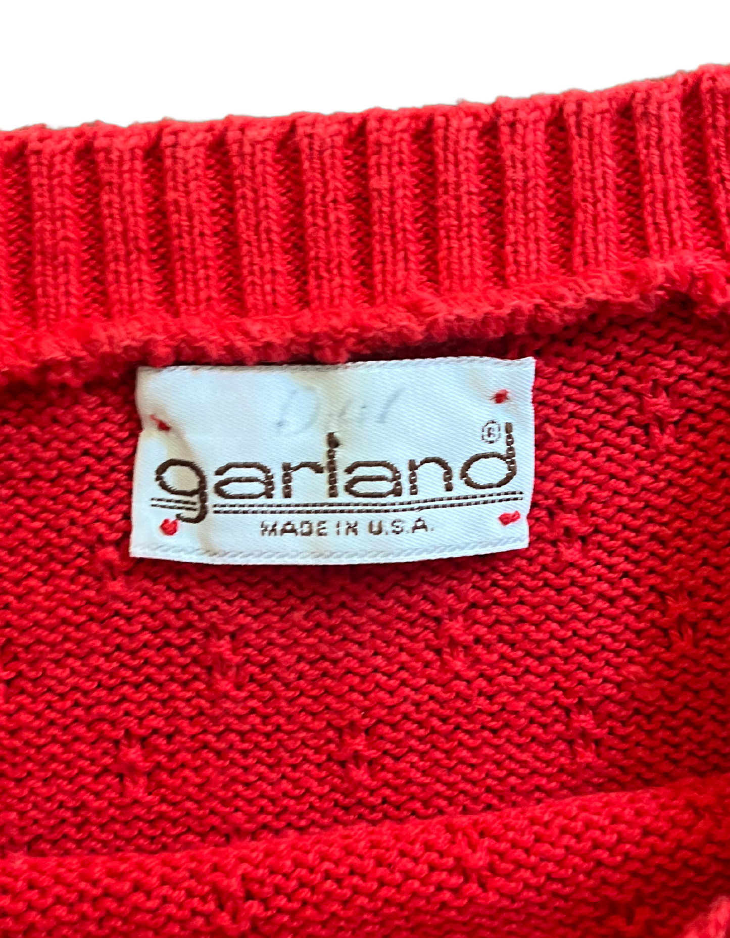 Tag image of red knit sweater vest on light background.