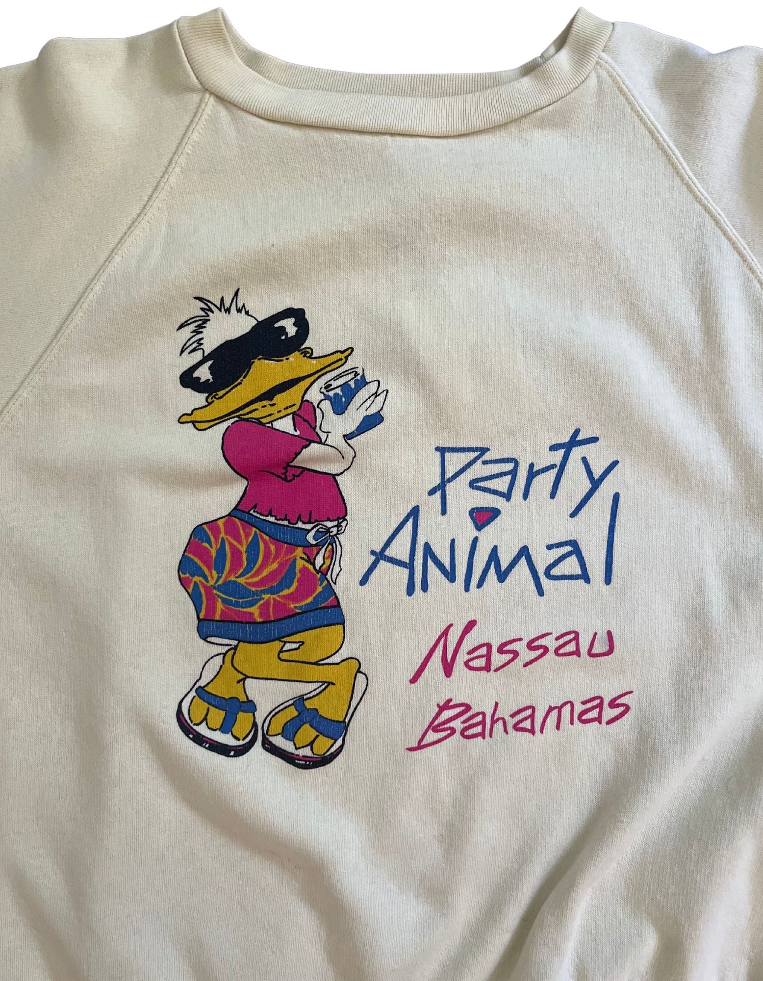 Close up Front image of light yellow sweatshirt that reads party animal, nassau bahamas featuring a duck wearing sunglasses on a white background.