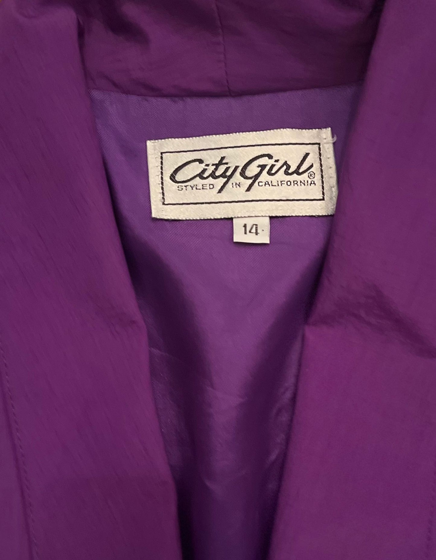 Close up image of tag on purple, hot pink and teal City girl blazer on white background.