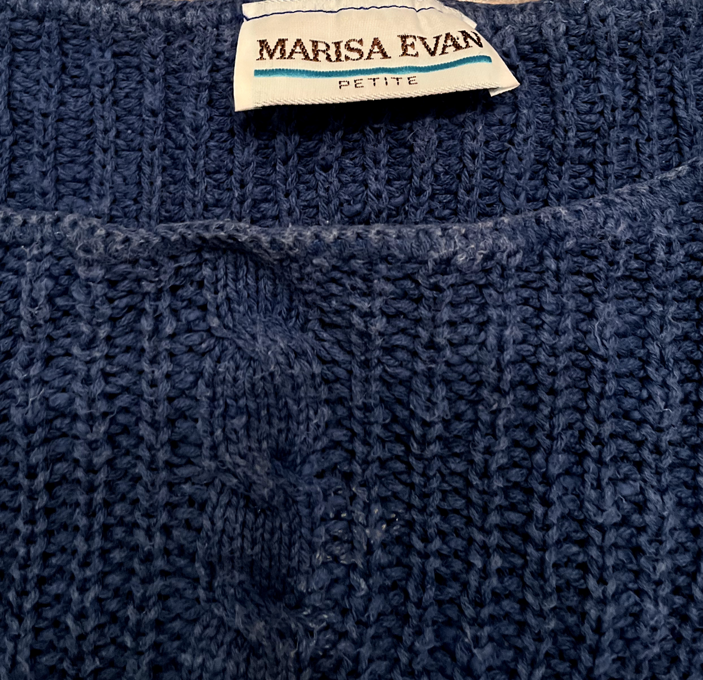 Close up shot of hangtag on vintage blue cable knit sweater vest.